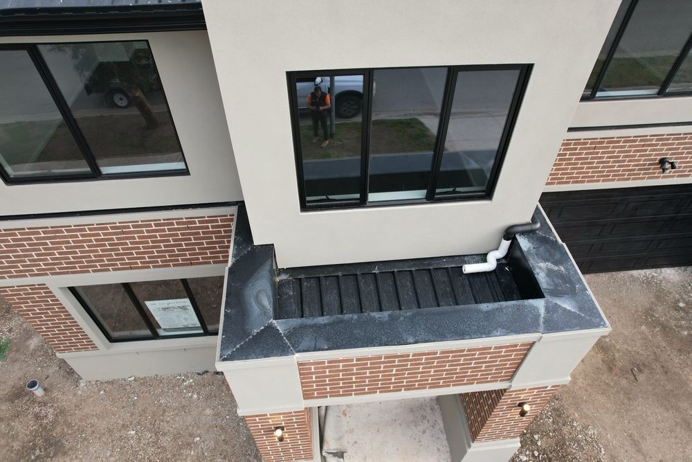 PVC downpipe junctions left unsealed above a balcony box gutter, Pakenham